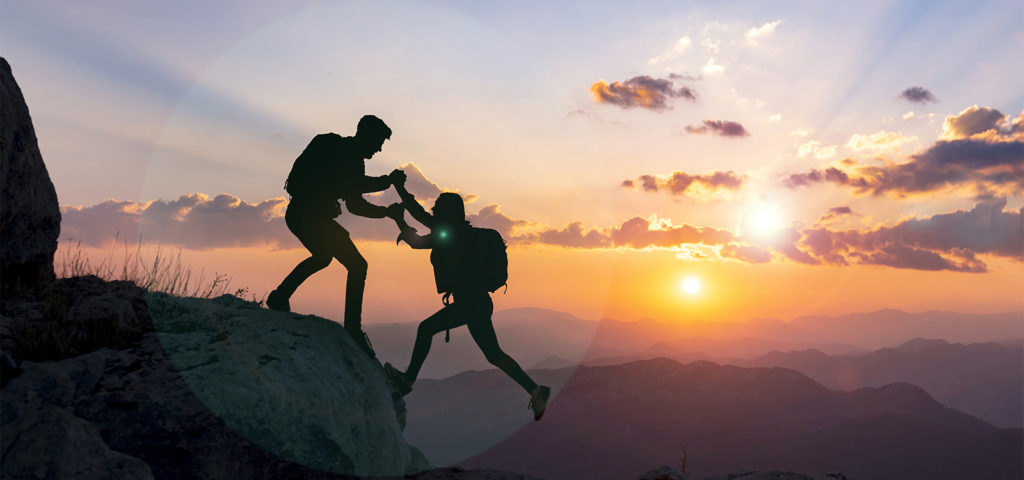 coach helping student climb a mountain